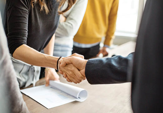 Two business professionals shaking hands over a conference table.