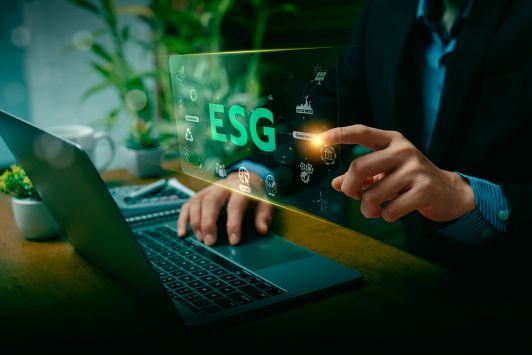 A person taps an ESG graphic above their laptop