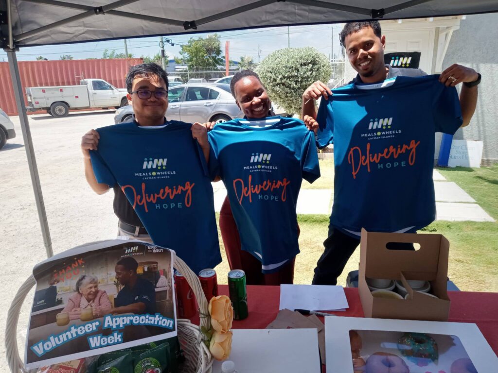 Three GCM employees holding Delivering Hope t-shirts at a volunteer event. 