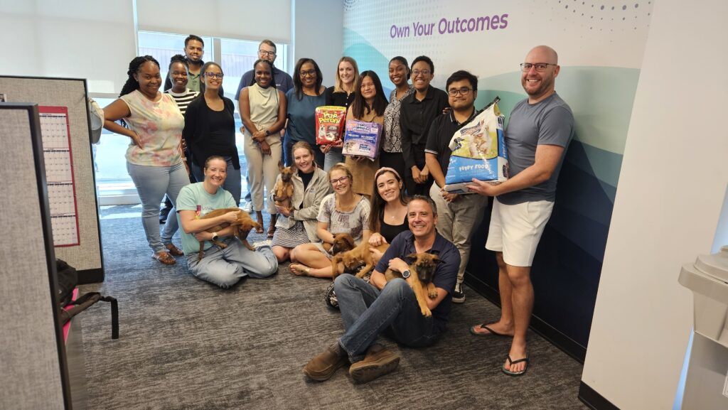 A group of GCM employees holding pet supplies and puppies to support a local shelter. 
