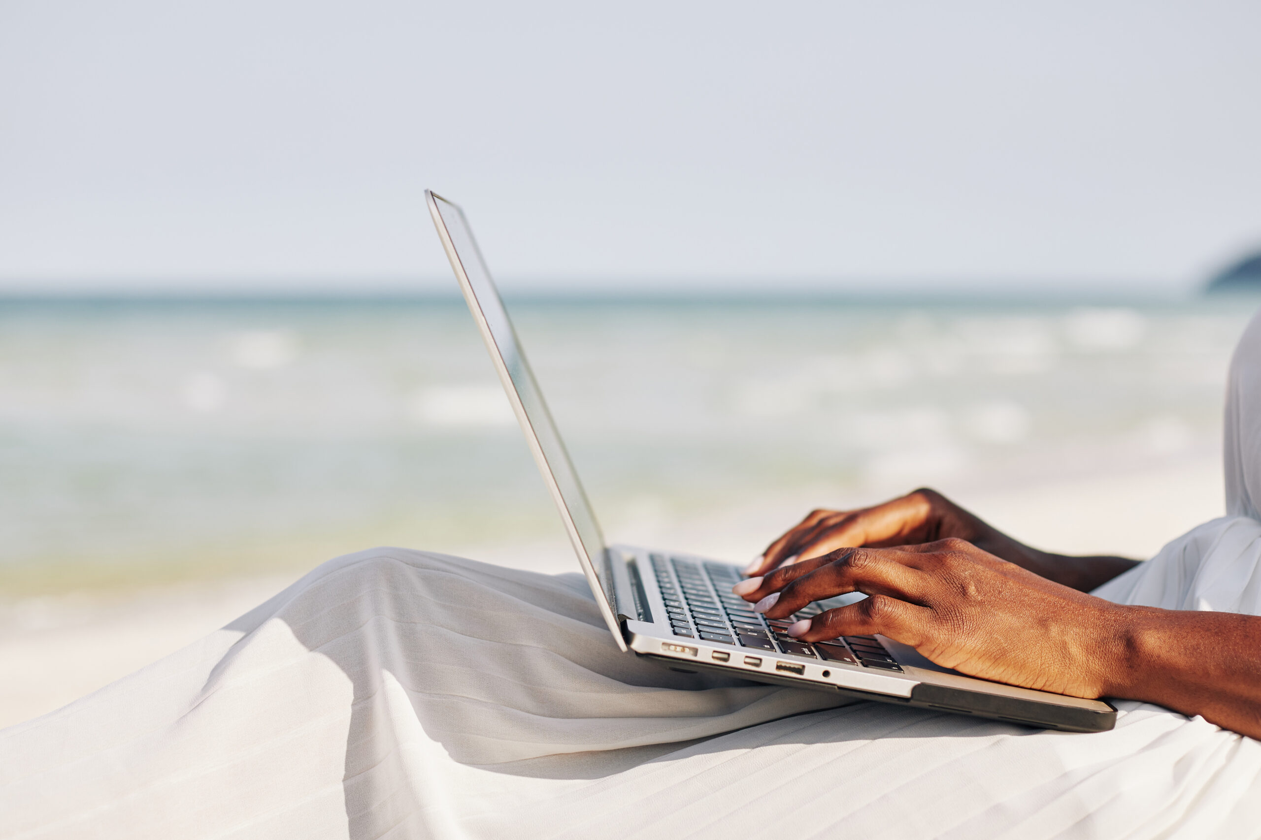 An employee works on their laptop from a tropical location.